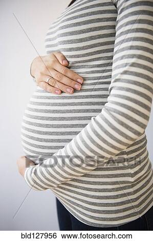 Stock Photograph - Pregnant Caucasian woman holding her belly. Fotosearch
