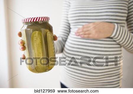 Stock Photo - Pregnant Caucasian woman holding jar of pickles. Fotosearch