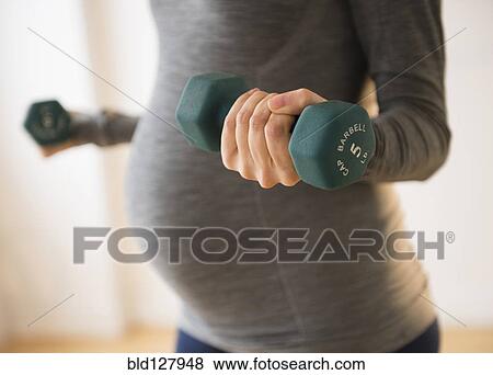 Stock Photo - Pregnant Caucasian woman lifting weights. Fotosearch