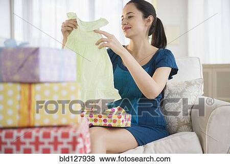 Stock Photo - Pregnant Caucasian woman opening baby shower gifts. Fotosearch
