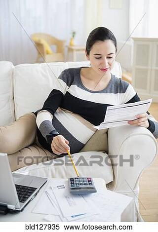 Stock Photography - Pregnant Caucasian woman paying bills. Fotosearch