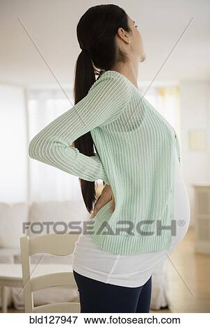 Stock Photo - Pregnant Caucasian woman stretching her back. Fotosearch