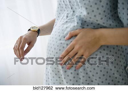 Stock Image - Pregnant Caucasian woman timing contractions in hospital. Fotosearch