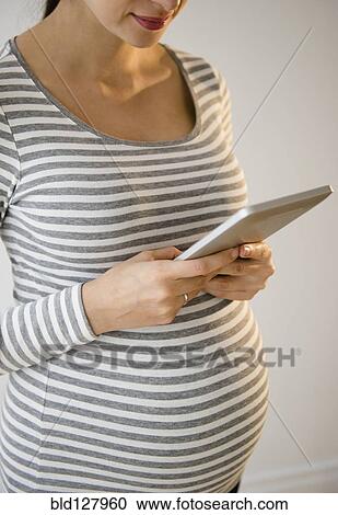 Stock Image - Pregnant Caucasian woman using digital tablet. Fotosearch