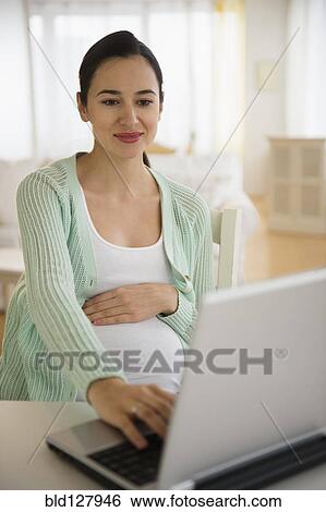 Stock Photograph - Pregnant Caucasian woman using laptop. Fotosearch