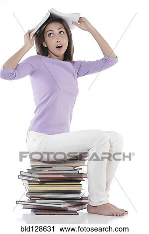 Stock Image - Woman sitting on stack of books. Fotosearch