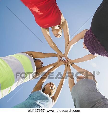 Stock Photo - Women putting hands together outdoors. Fotosearch