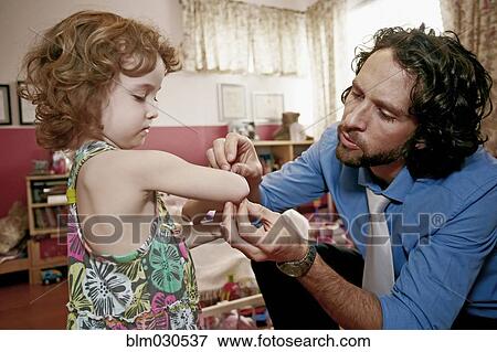 Stock Photo - Caucasian father examining daughter's scrape. Fotosearch