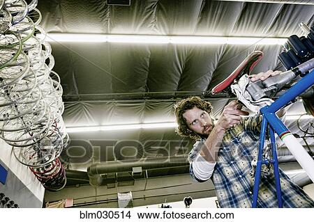 Picture - Caucasian man smiling in bicycle repair shop. Fotosearch