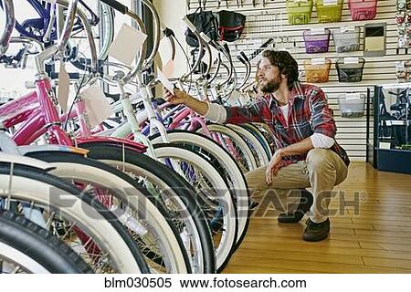 Stock Photography - Caucasian man working in bicycle shop. Fotosearch