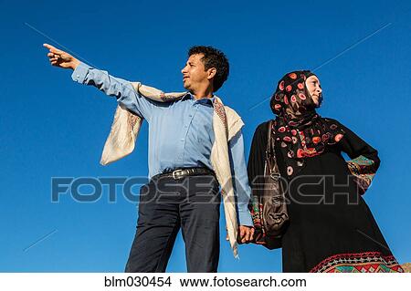 Picture - Couple holding hands against blue sky. Fotosearch