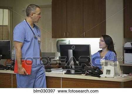 Stock Photo - Doctor speaking to nurse in hospital. Fotosearch
