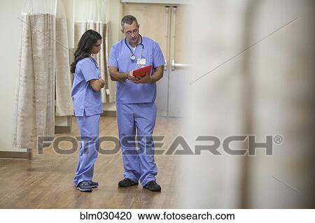 Stock Image - Doctors using digital tablet in hospital corridor. Fotosearch