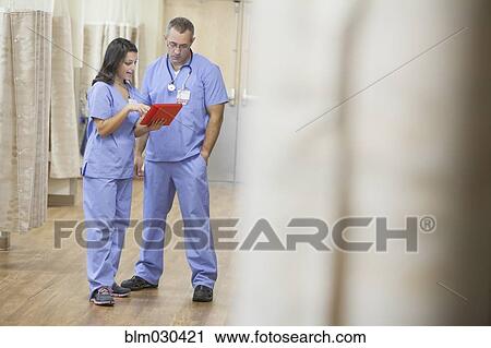 Stock Image - Doctors using digital tablet in hospital corridor. Fotosearch