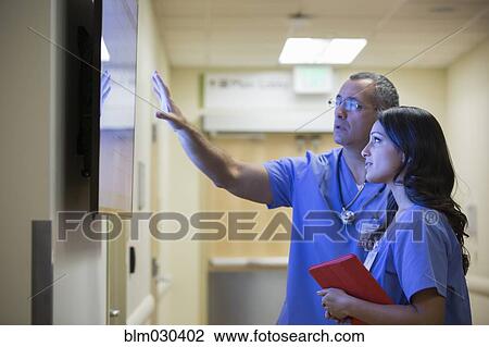 Doctors watching monitor in hospital corridor View Large Photo Image Stock Image - Doctors watching monitor in hospital corridor. Fotosearch