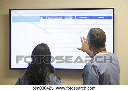 Doctors watching monitor in hospital corridor View Large Photo Image Stock Photography - Doctors watching monitor in hospital corridor. Fotosearch