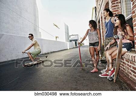 Stock Photo - Friends riding longboards on city street. Fotosearch