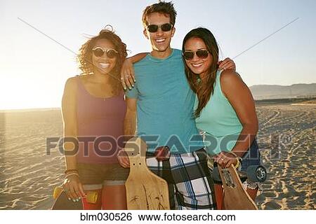 Stock Photograph - Friends smiling on beach. Fotosearch