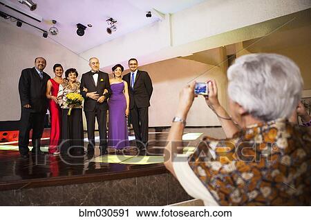 Stock Image - Hispanic family taking pictures at wedding reception. Fotosearch