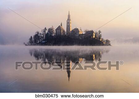 Stock Photography - Mist shrouding island on Lake Bled at sunrise, Bled, Gorenjska, Slovenia. Fotosearch