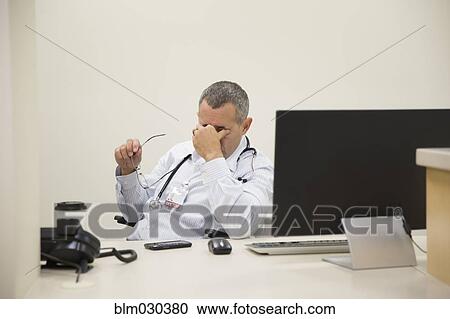 Mixed race doctor rubbing his eyes in office View Large Photo Image Stock Image - Mixed race doctor rubbing his eyes in office. Fotosearch