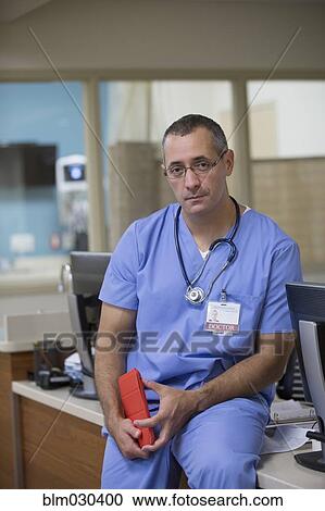 Stock Image - Mixed race doctor sitting in hospital reception. Fotosearch