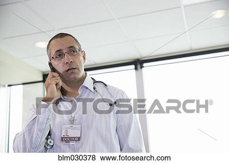 Stock Photo - Mixed race doctor talking on cell phone in hospital. Fotosearch