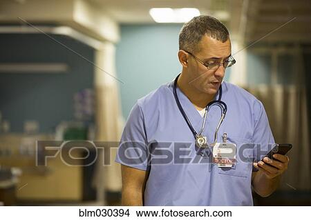 Picture - Mixed race doctor using cell phone in hospital. Fotosearch