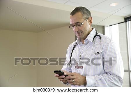 Mixed race doctor using cell phone in hospital View Large Photo Image Stock Photo - Mixed race doctor using cell phone in hospital. Fotosearch