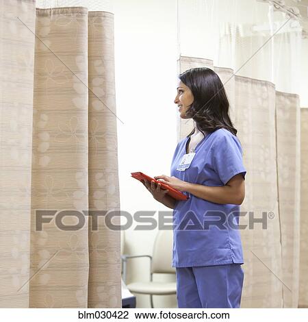 Stock Image - Mixed race doctor using digital tablet in hospital corridor. Fotosearch