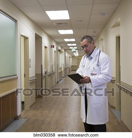 Mixed race doctor using digital tablet in hospital corridor View Large Photo Image Stock Photo - Mixed race doctor using digital tablet in hospital corridor. Fotosearch