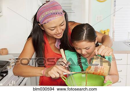 Picture - Mixed race mother and daughter baking in kitchen. Fotosearch