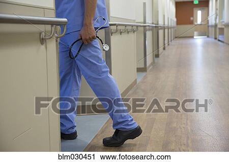 Stock Image - Mixed race nurse carrying stethoscope in hospital. Fotosearch