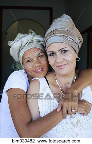 Stock Image - Mixed race women hugging. Fotosearch