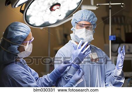 Nurse adjusting surgeon's gloves in operating room View Large Photo Image Stock Image - Nurse adjusting surgeon's gloves in operating room. Fotosearch