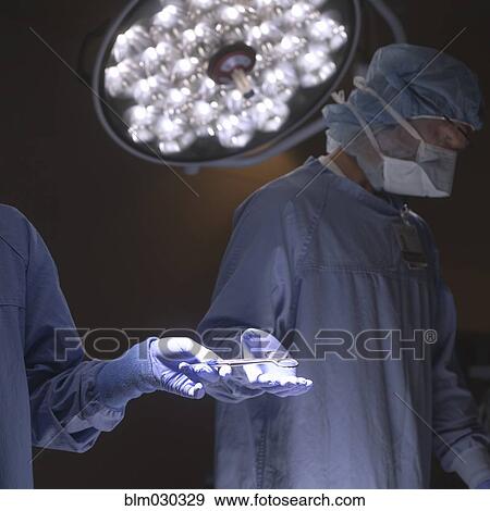 Stock Photo - Nurse handing implements to surgeon in operating room. Fotosearch