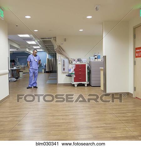 Stock Image - Nurse using cell phone in hospital corridor. Fotosearch