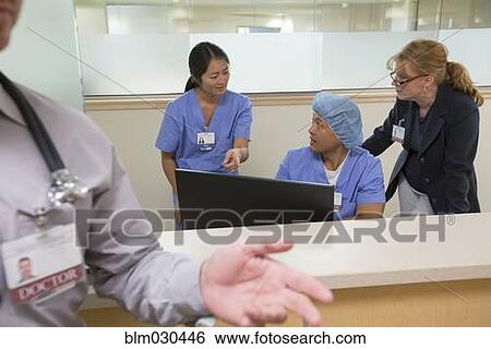 Nurses and doctors working at nurses station in hospital View Large Photo Image Stock Photograph - Nurses and doctors working at nurses station in hospital. Fotosearch