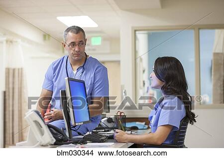 Picture - Nurses talking at nurses station. Fotosearch