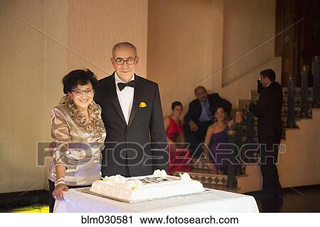 Stock Image - Senior newlywed couple smiling with wedding cake. Fotosearch
