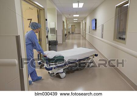 Stock Photo - Surgeon pushing gurney in hospital corridor. Fotosearch