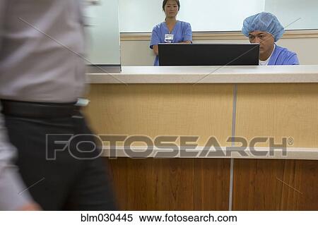 Stock Photography - Surgeon working at nurses station of hospital. Fotosearch