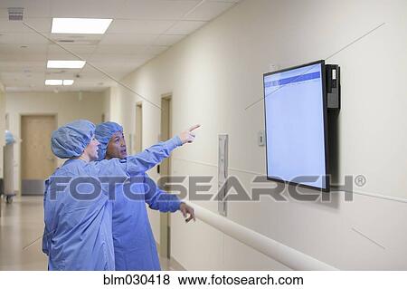 Stock Photo - Surgeons watching monitor in hospital corridor. Fotosearch