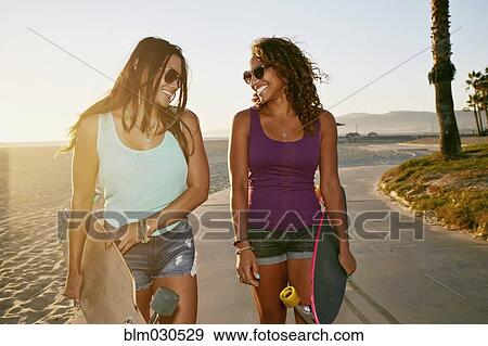 Women carrying longboards on beach View Large Photo Image Stock Photo - Women carrying longboards on beach. Fotosearch