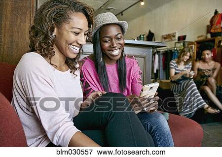 Stock Photo - Women using cell phone in store. Fotosearch