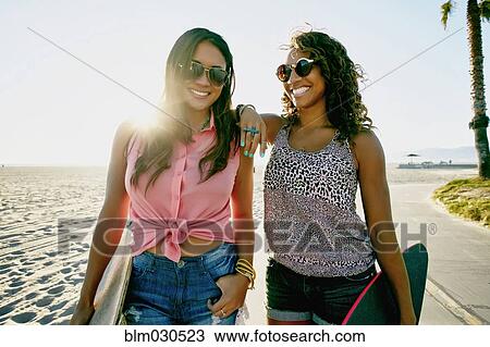 Stock Image - Women walking together on beach. Fotosearch