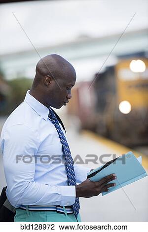 Stock Image - African American businessman waiting for train. Fotosearch