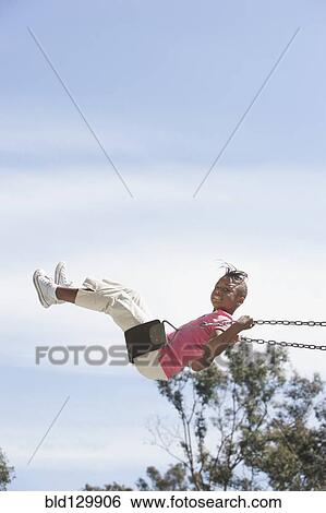 Stock Photograph - African American girl playing on swing. Fotosearch