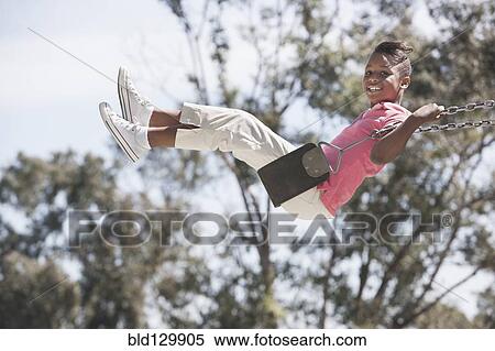 Stock Photography - African American girl playing on swing. Fotosearch