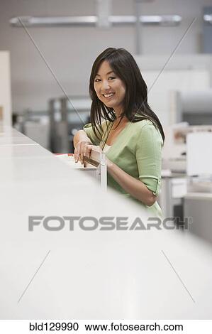 Asian businesswoman smiling in office View Large Photo Image Stock Image - Asian businesswoman smiling in office. Fotosearch